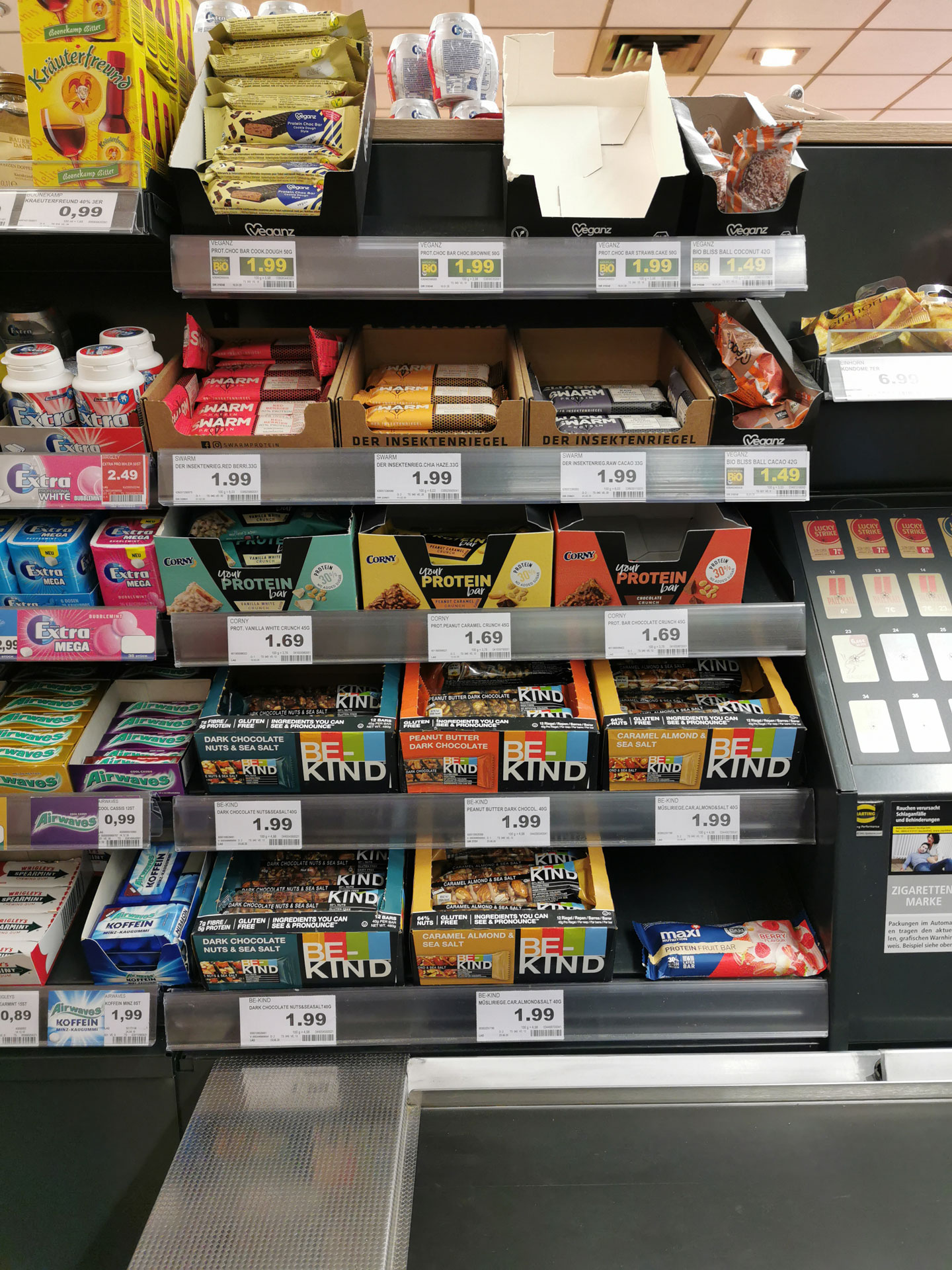 Foto: BE-KIND Riegel im Süßwarenregal neben Mars, Twix und Kaugummis platziert.