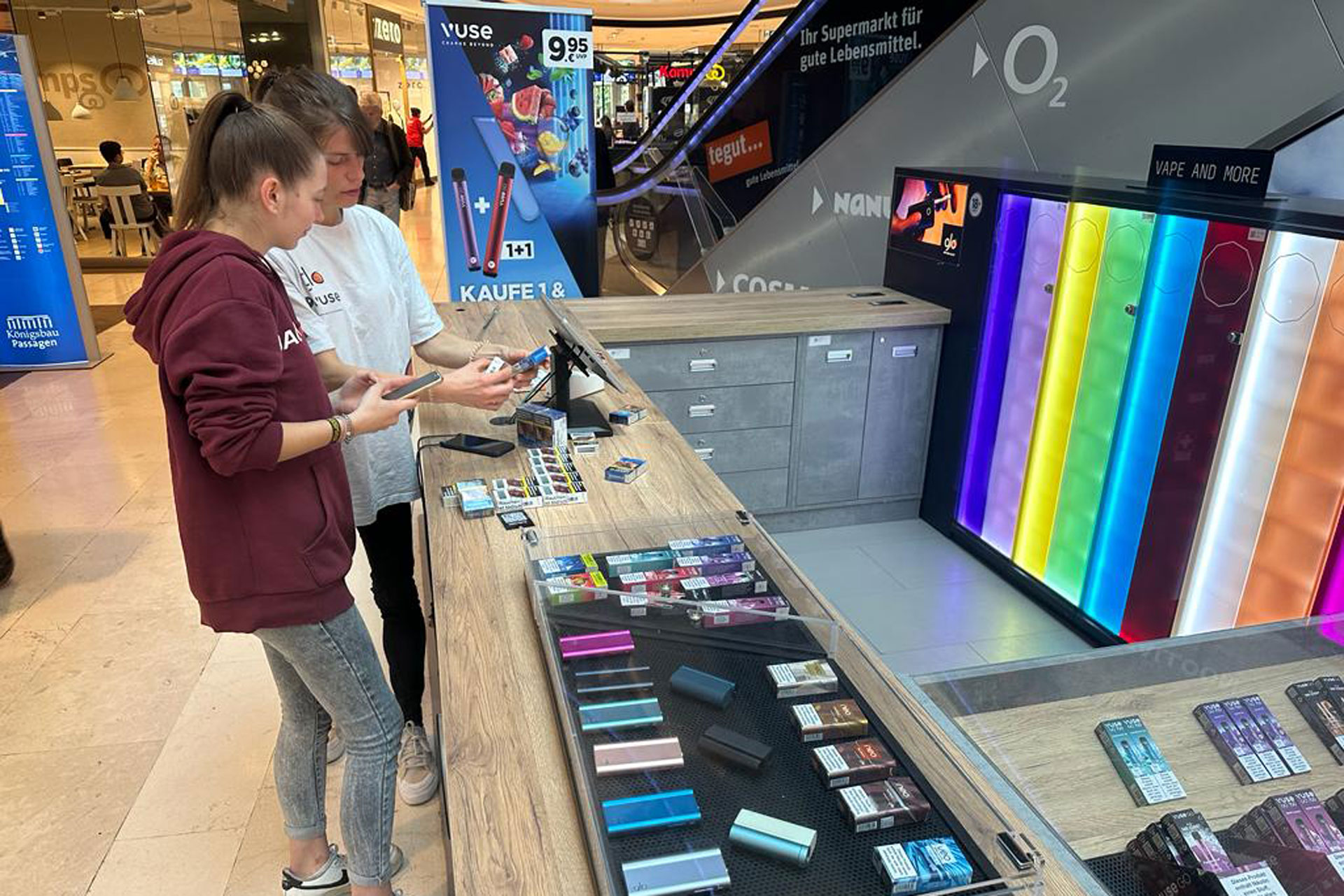 Foto: Zwei Personen an einem Vuse-Verkaufsstand in einem Einkaufszentrum, schauen sich Produkte an.